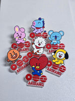 Los siete pines de BT21 de la caja BTS, cada uno con el logo Arirang: Cooky, Mang, Koya, RJ, Shooky, Tata y Chimmy