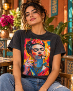 Polera negra con el retrato pop de Frida Kahlo fumando un puro, con flores en el pelo y collares dorados