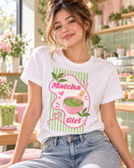 Polera blanca con el diseño Matcha Girl de la lámina Matcha Lover, en una cafetería con un vaso de matcha