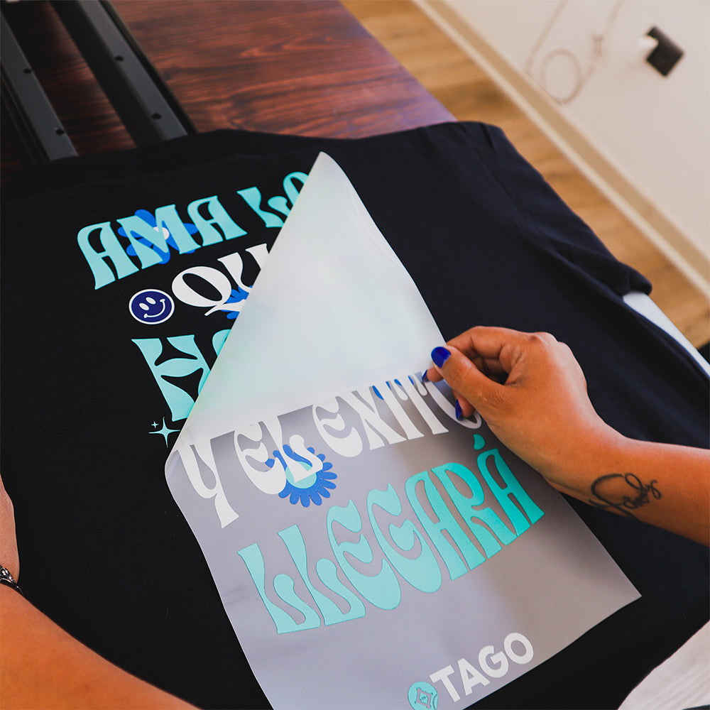Retirando el film de la lámina DTF: el diseño queda estampado en la polera negra