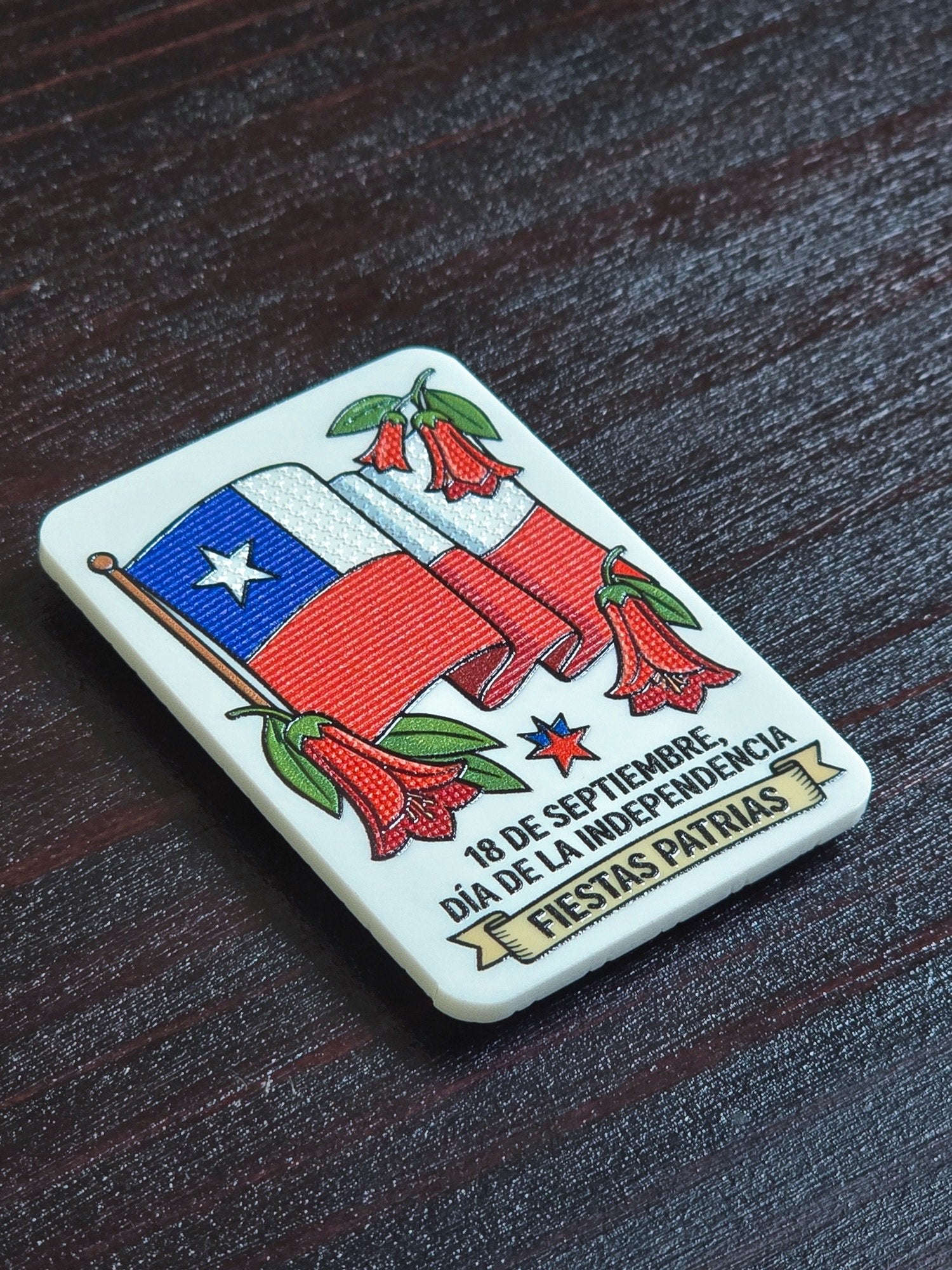 Detalle en ángulo del imán de bandera y copihues, donde se ve el relieve