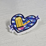 Pin de corazón a cuadros celestes con un lápiz y estrellas, fondo blanco